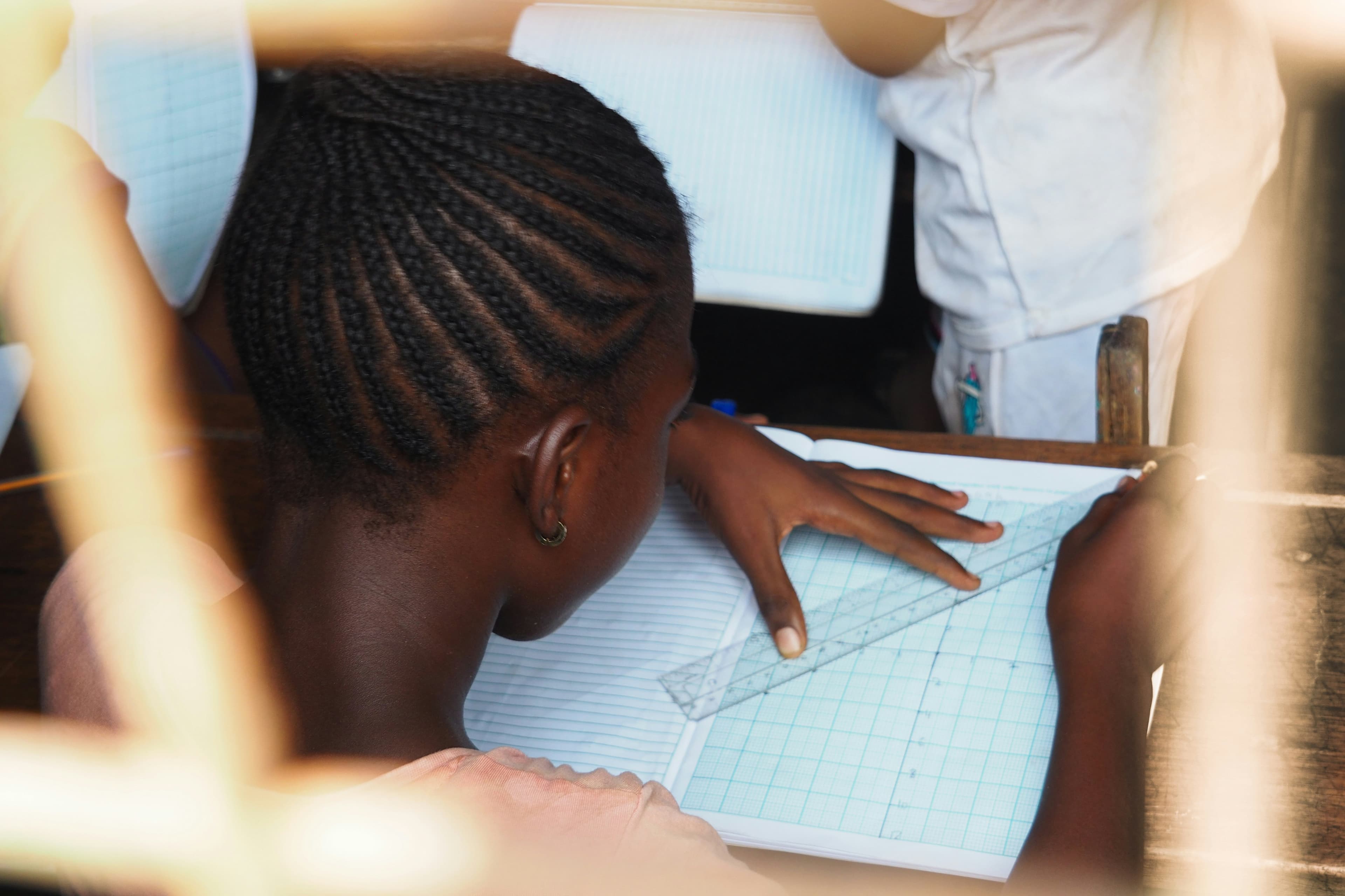 A student working carefully with a ruler on graph paper